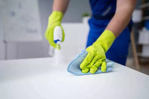 Technician removing stain from the surface wearing rubber hand gloves